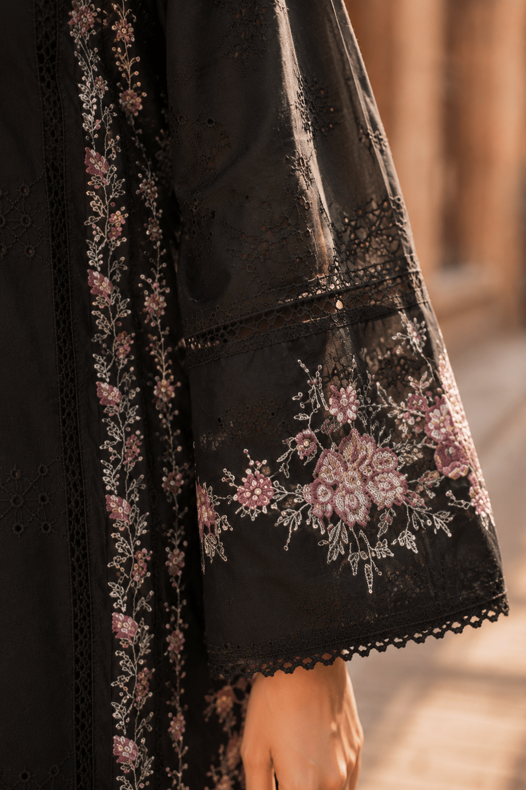 Close-up sleeve detail of black embroidered lawn suit with floral motifs, lace cuff finishing and premium Pakistani fashion craftsmanship.