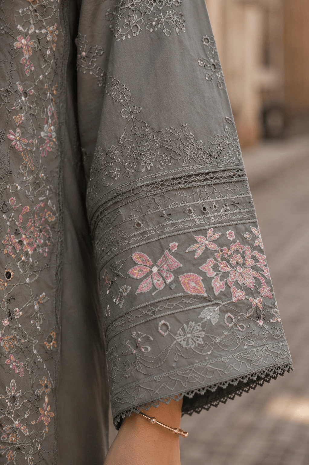 Close-up sleeve embroidery and cuff lace detail of grey Pakistani lawn suit highlighting premium fabric texture and floral design.