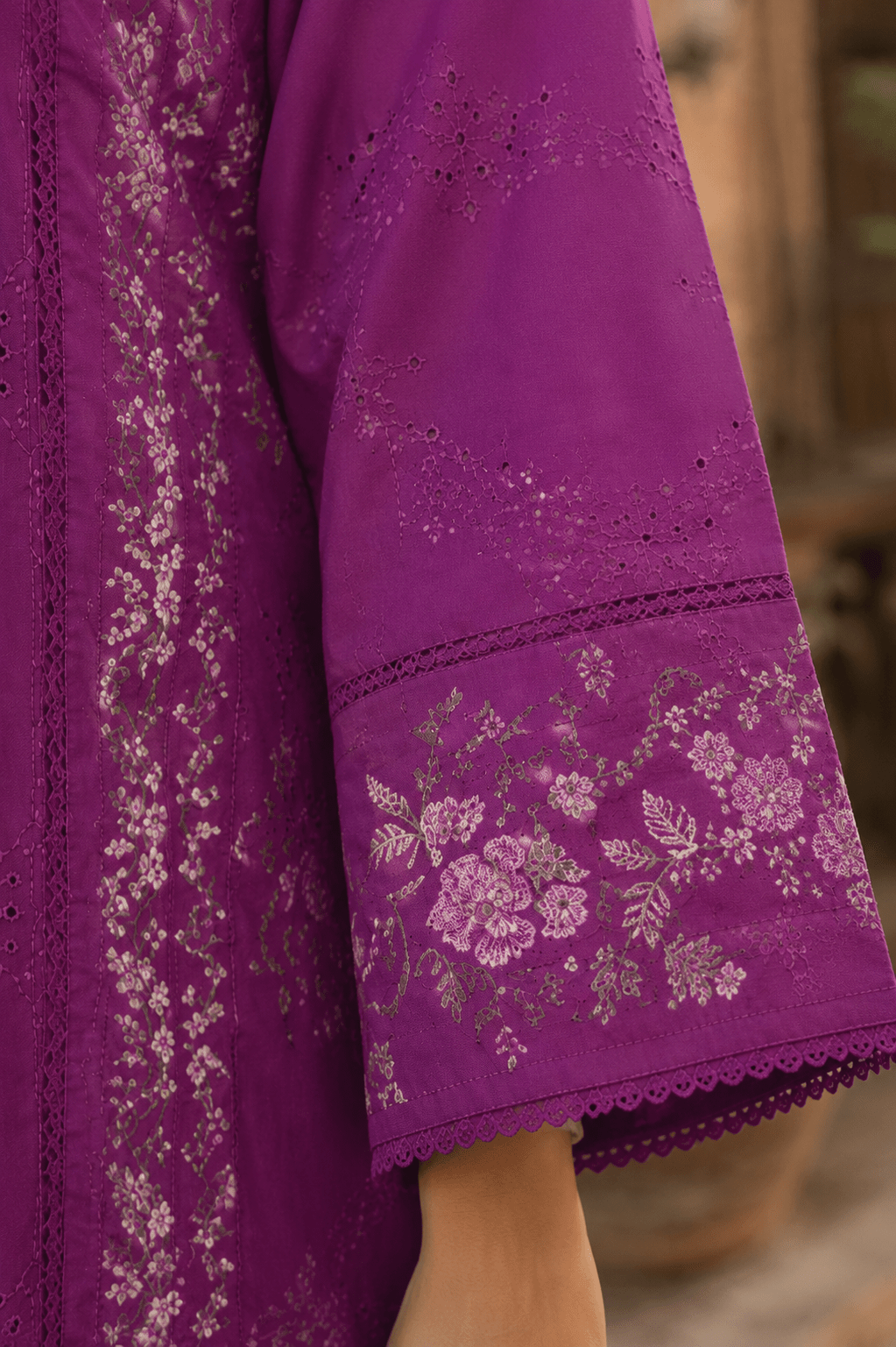 Close-up sleeve embroidery and cuff detail of purple Pakistani lawn suit showcasing premium fabric texture, floral motifs and lace finishing.