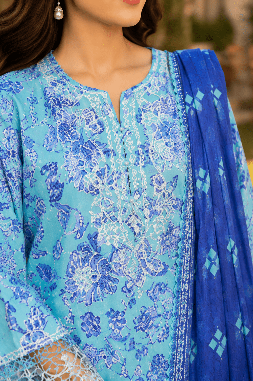 Close-up neckline and front panel detail of Mehrbano aqua blue lawn suit featuring floral prints and lace finishing.